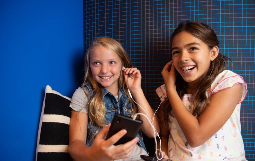 Girls listening to music on their Gabb cellphone for kids