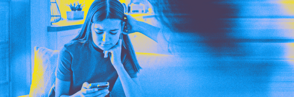 distraught teen looking at smartphone being comforted by her mom